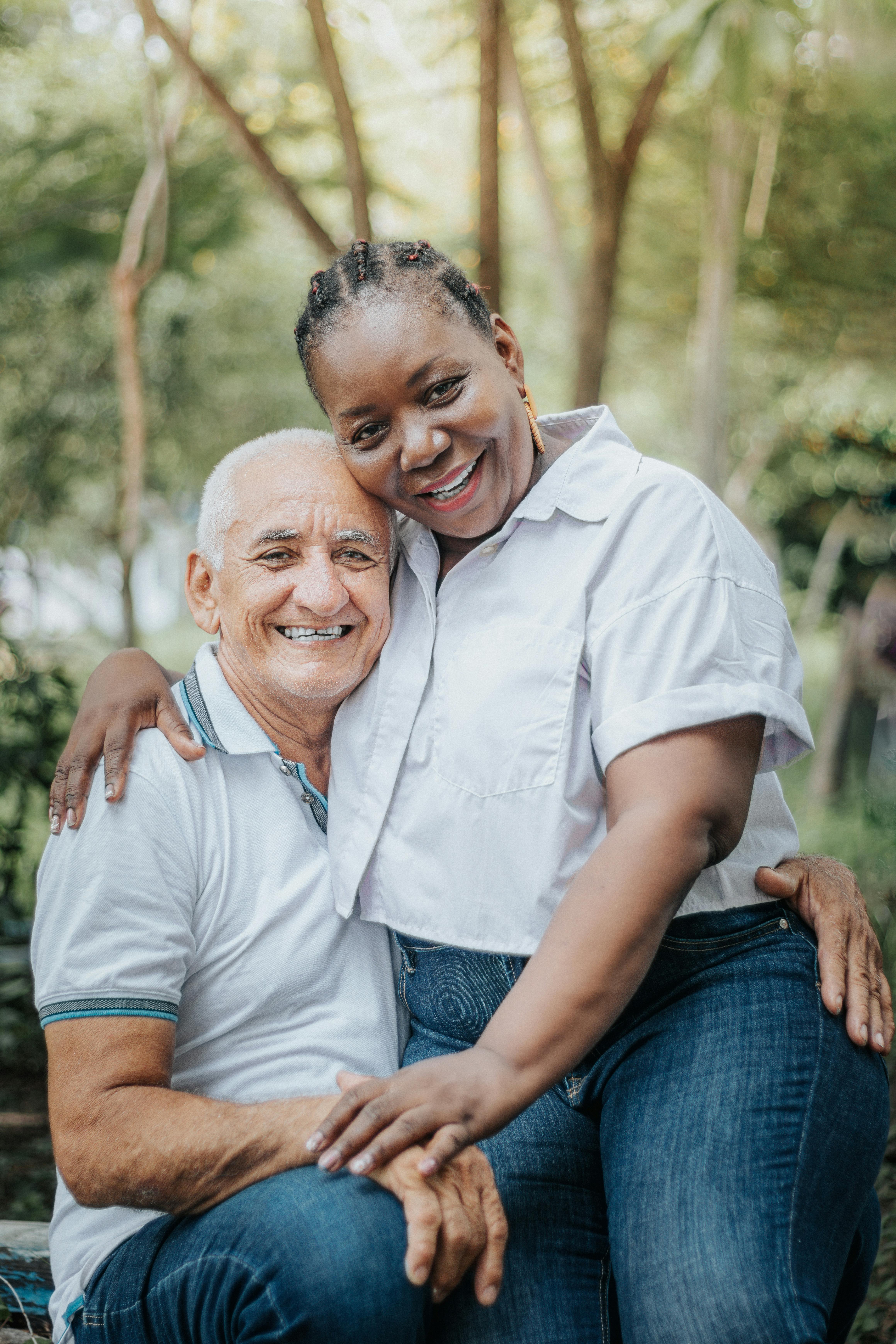 Two people smiling together outdoors, with their arms around one another