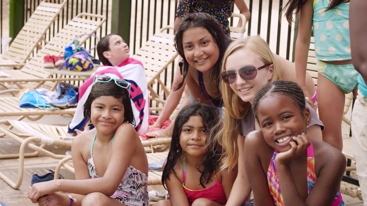Happy Trails campers and a counselor smiling together beside a pool
