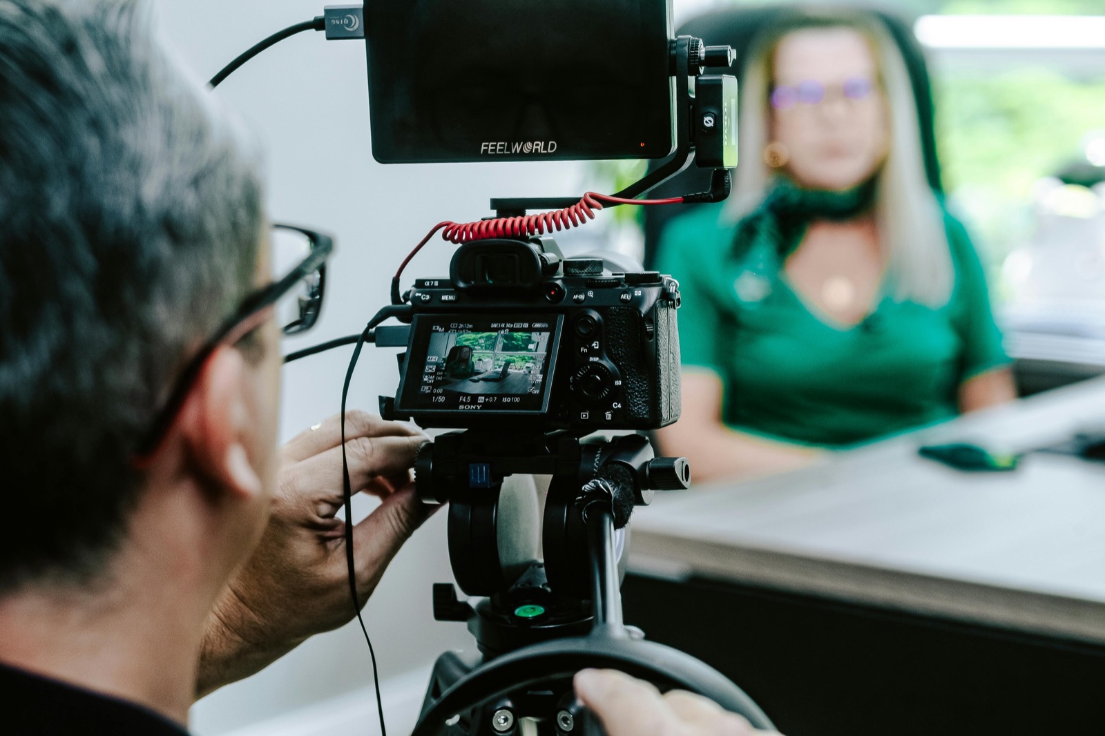 A filmmaker recording a seated conversation in a bright room
