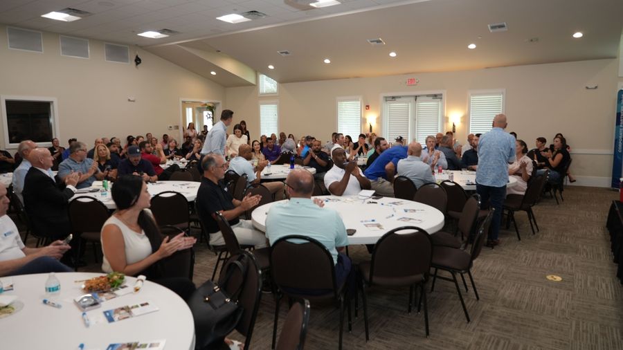 Wide view of GOBA event attendees gathered around round tables in the meeting room.