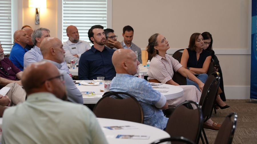 A group of seated attendees watches the presentation at the GOBA event.
