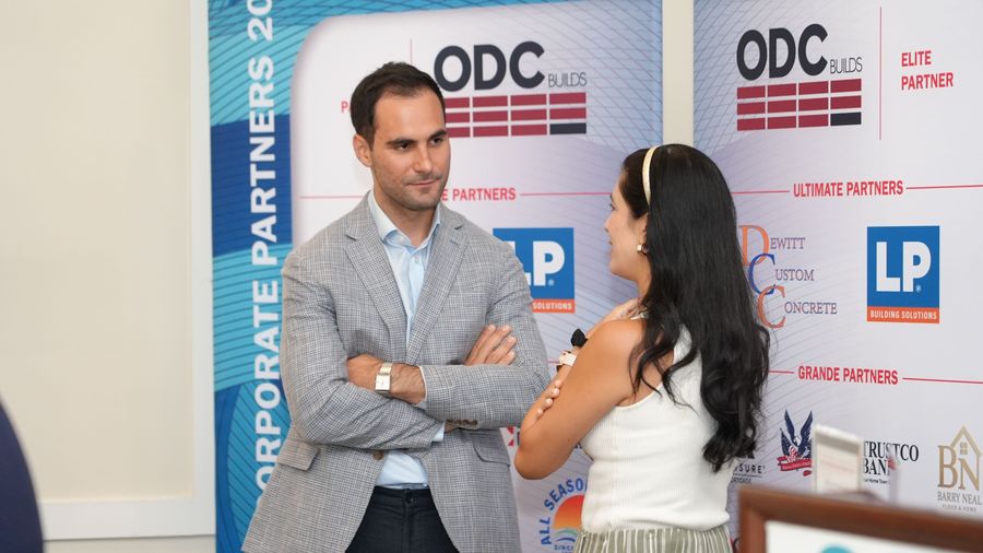 Two attendees talk in front of the GOBA sponsor backdrop.
