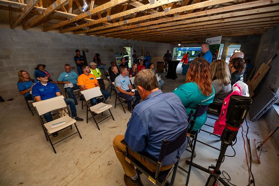 Participants seated in a circle inside a house under construction for Habitat’s Executive Build gathering.