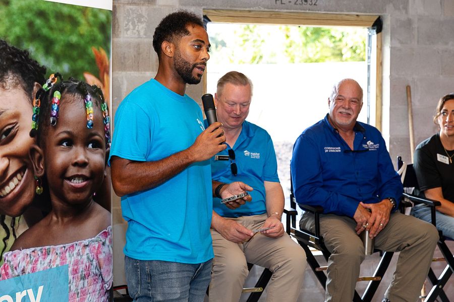 A speaker in a turquoise shirt addressing the seated group.