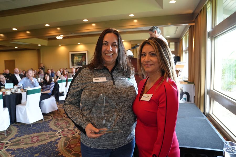 Two guests with a glass award at the HomeAid breakfast.