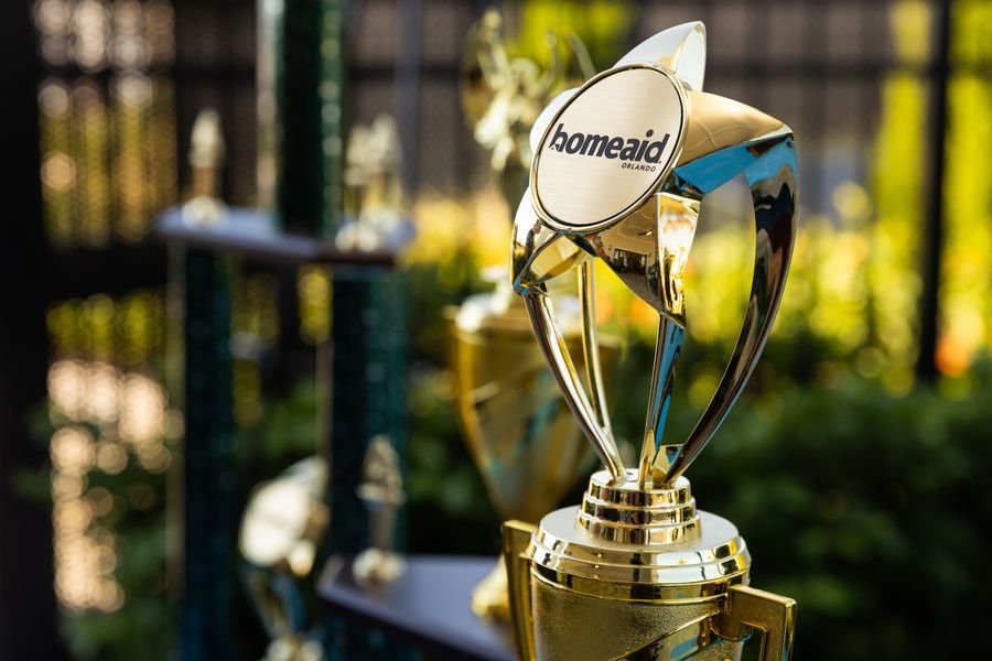 Close-up of a gold HomeAid trophy displayed at the cornhole tournament.