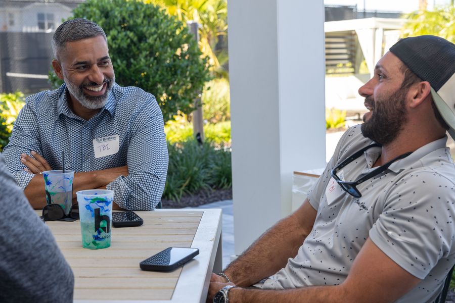 Two attendees share a conversation at a table under the pavilion.