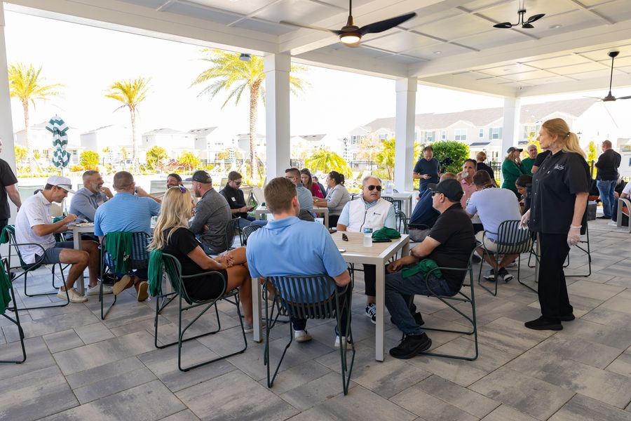 Tournament guests gather around tables beneath the outdoor pavilion.