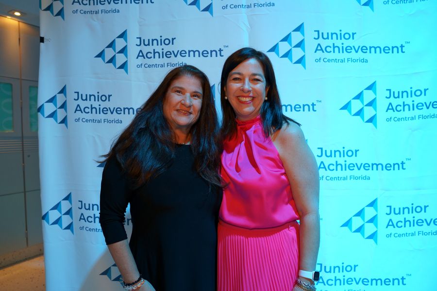 Two guests posing in front of a Junior Achievement backdrop.
