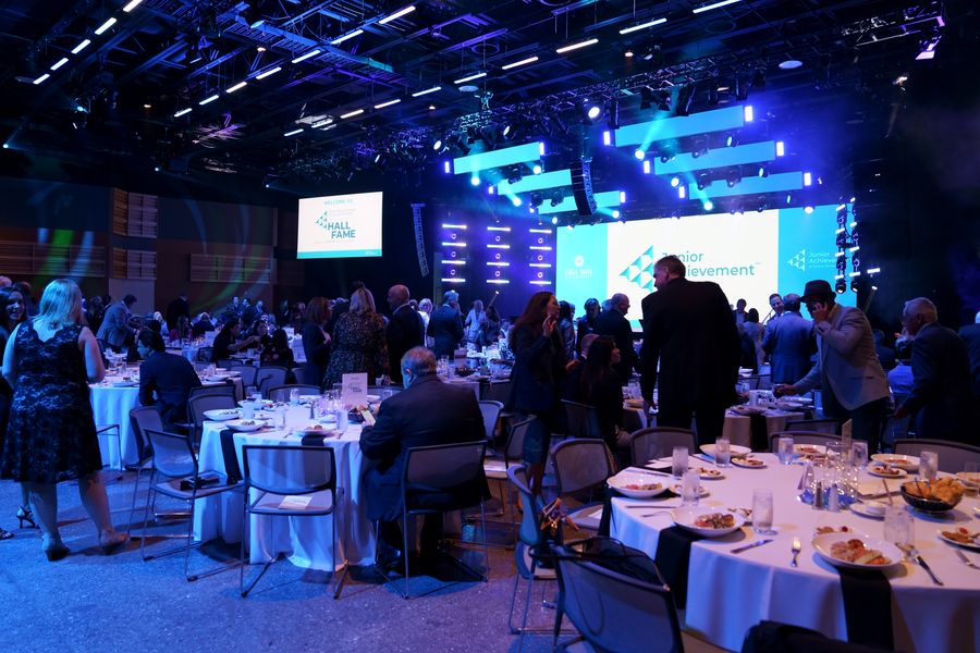 Wide view of dinner tables and the illuminated event stage.