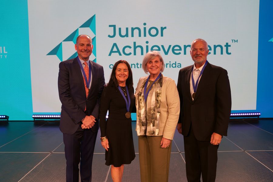 Four guests posing together on the Junior Achievement stage.