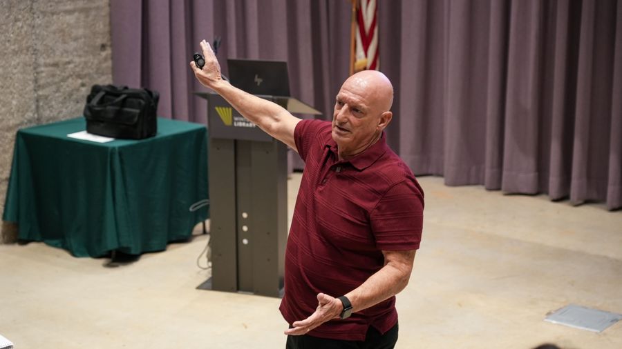 A presenter gestures toward the screen during the Inside Google Ads workshop.