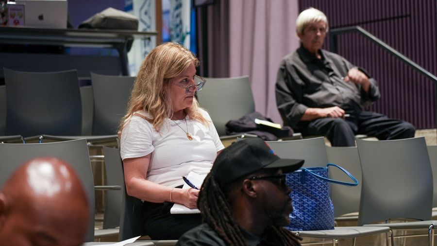 A seated attendee writes notes while listening to the workshop.