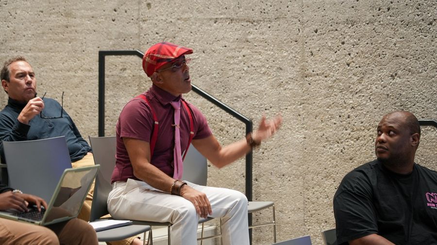 An attendee in a red cap gestures during the workshop discussion.