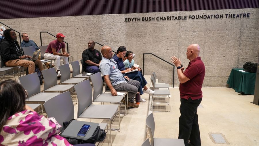 The workshop presenter leads a discussion with attendees seated in the tiered theater.