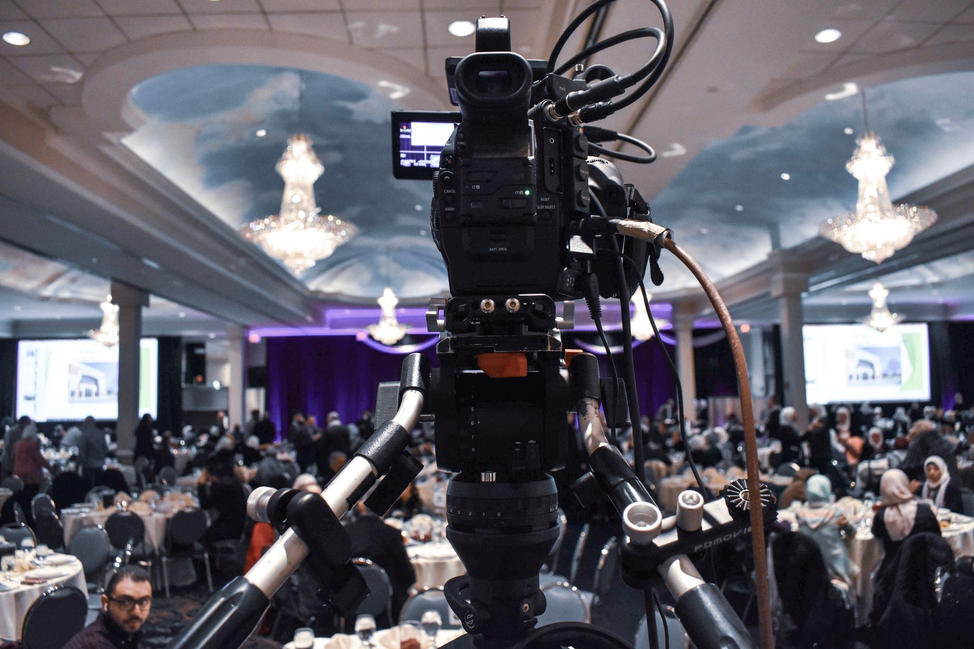 A professional video camera overlooking a ballroom event.