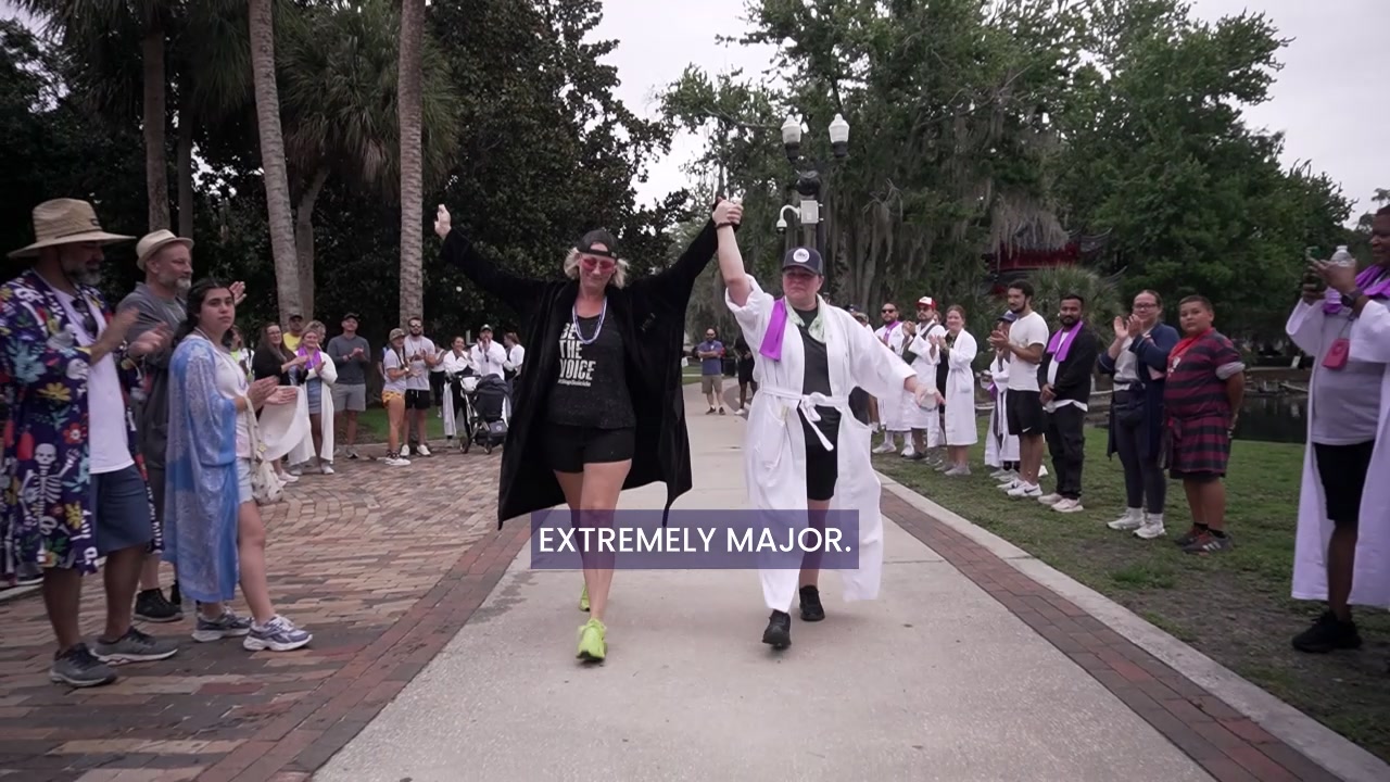 Robe Walk participants walking between two lines of supporters in a park